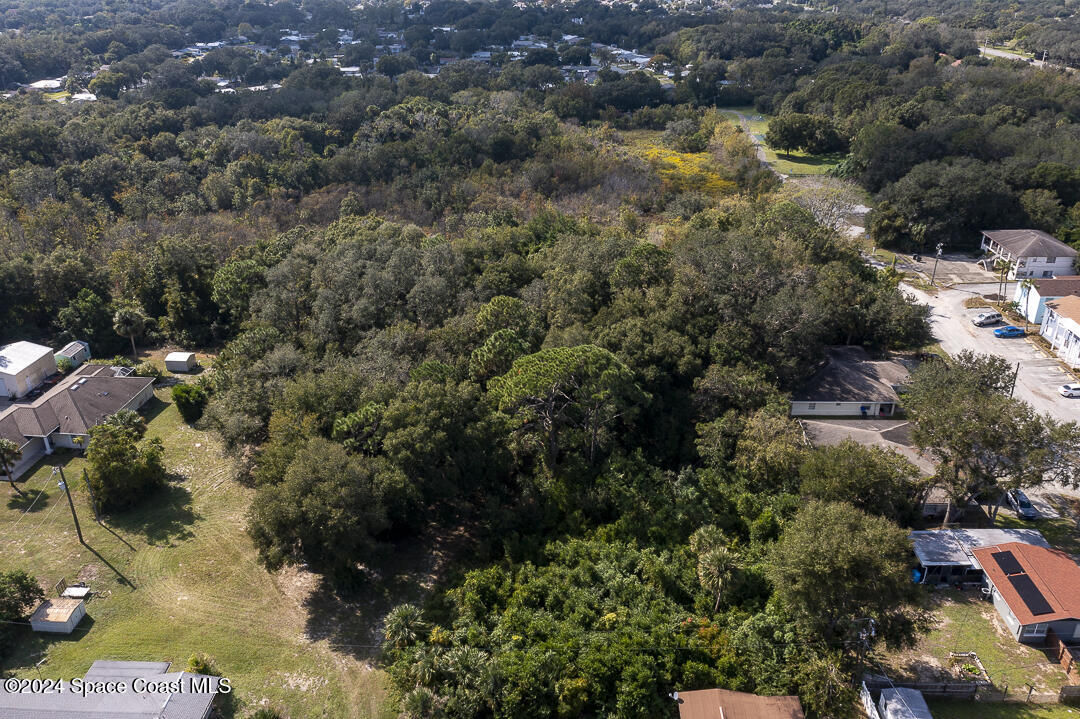 an aerial view of residential houses with outdoor space and trees