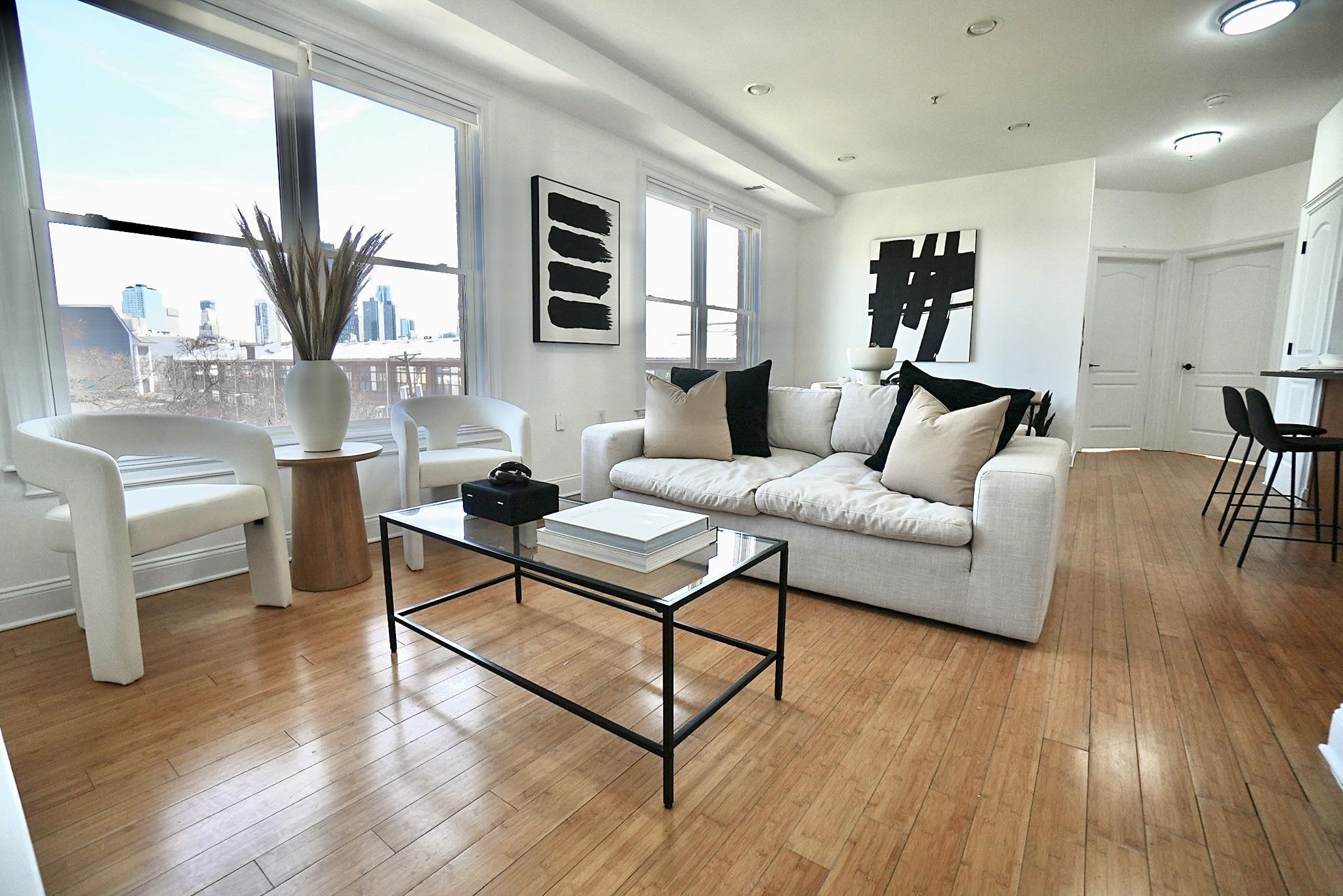 a living room with furniture floor to ceiling window and wooden floor