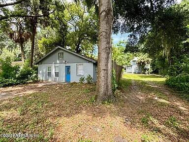 a view of a house with a yard and large trees