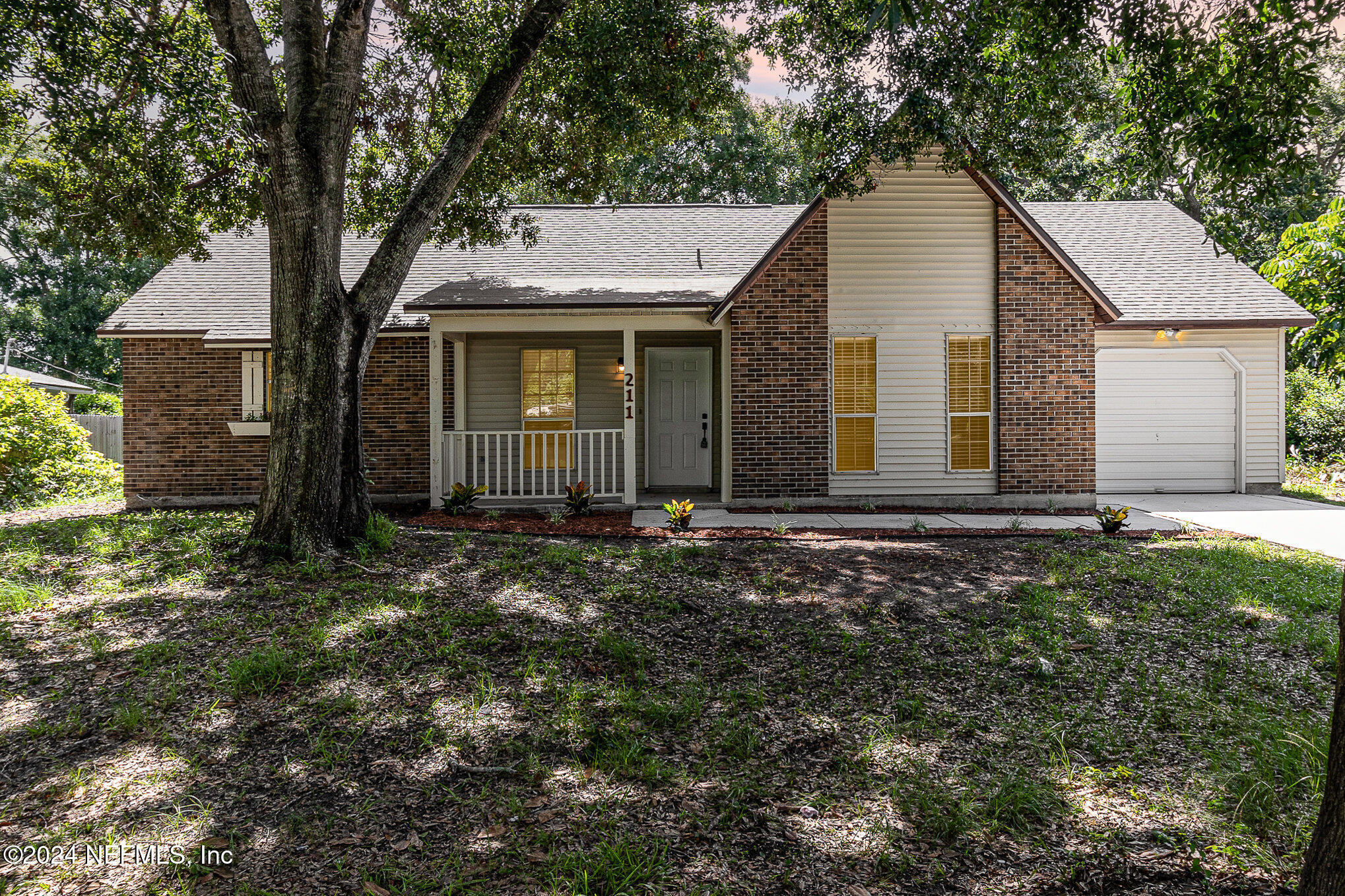 a view of a house with a yard and large tree