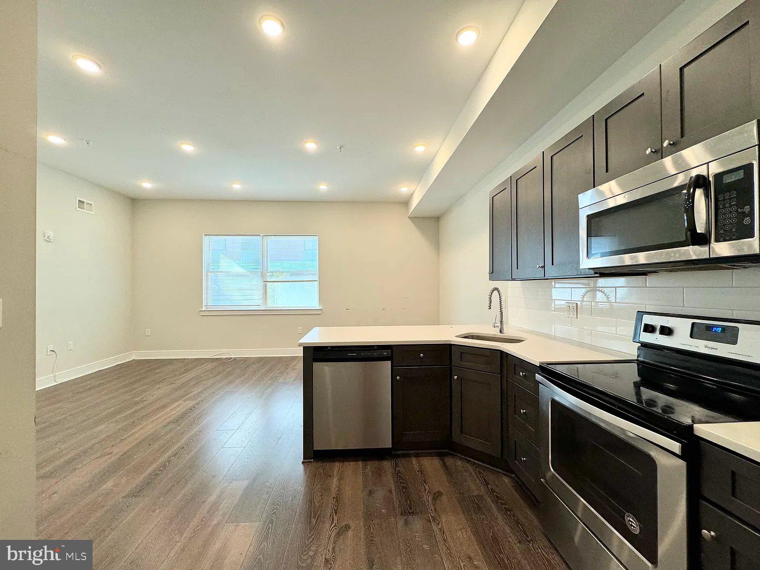 a kitchen with stainless steel appliances granite countertop a sink a stove a microwave and wooden floors