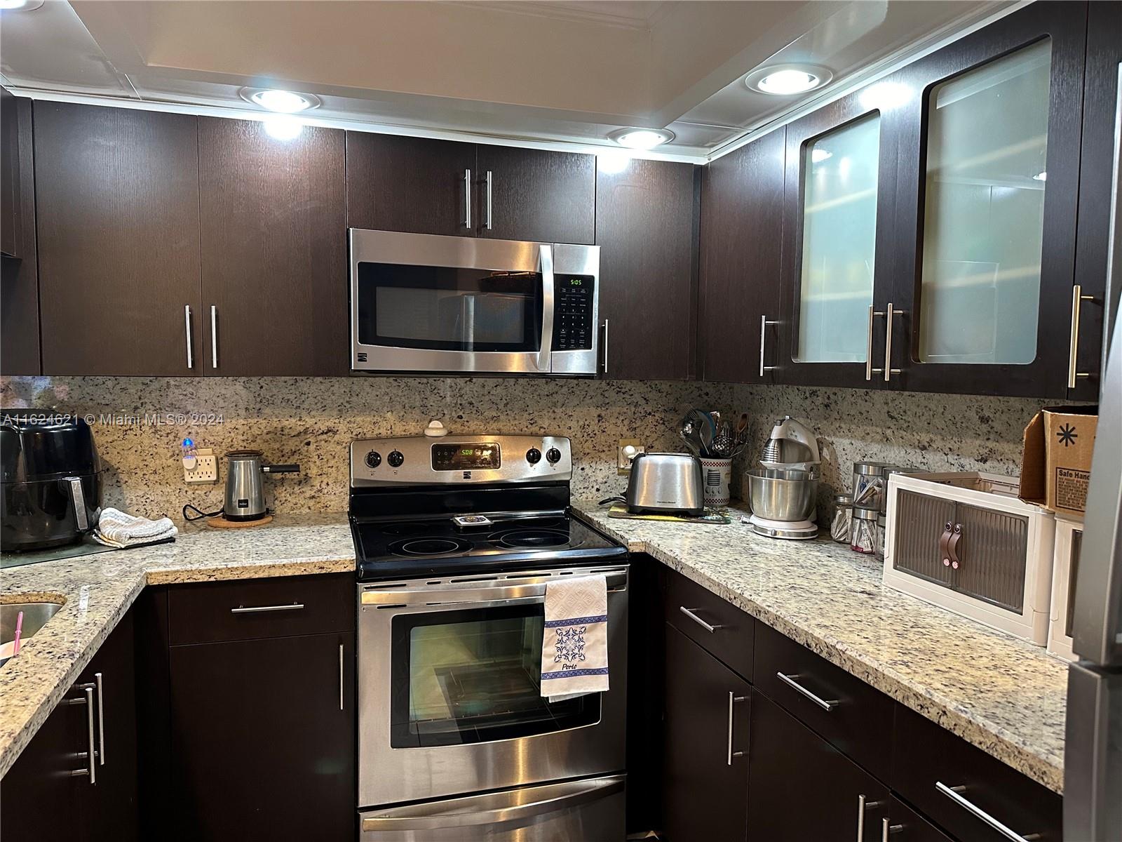 a kitchen with stainless steel appliances granite countertop a sink stove and microwave