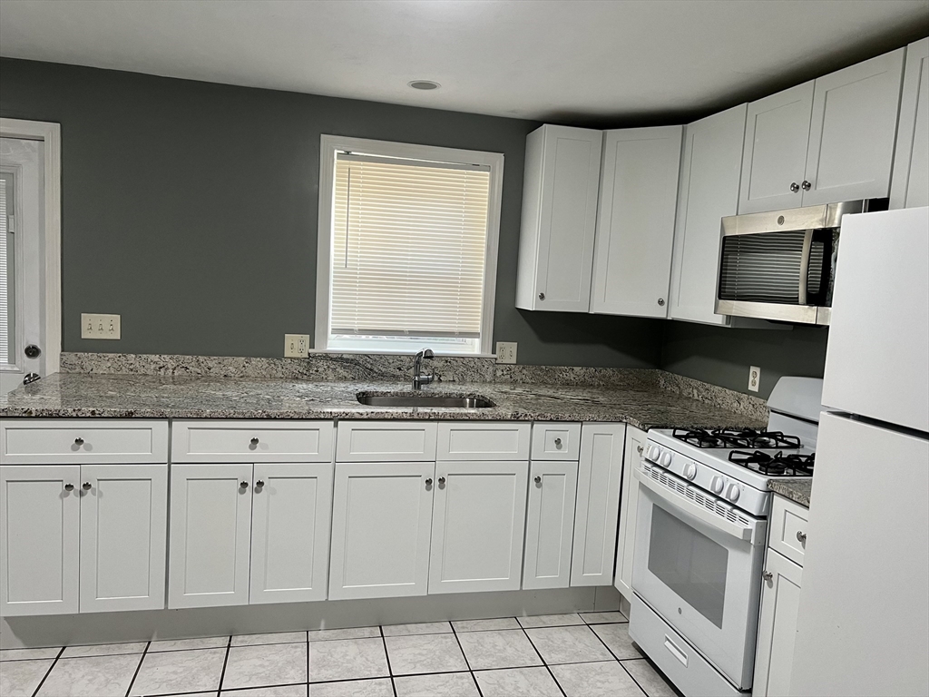 a kitchen with granite countertop white cabinets and white appliances