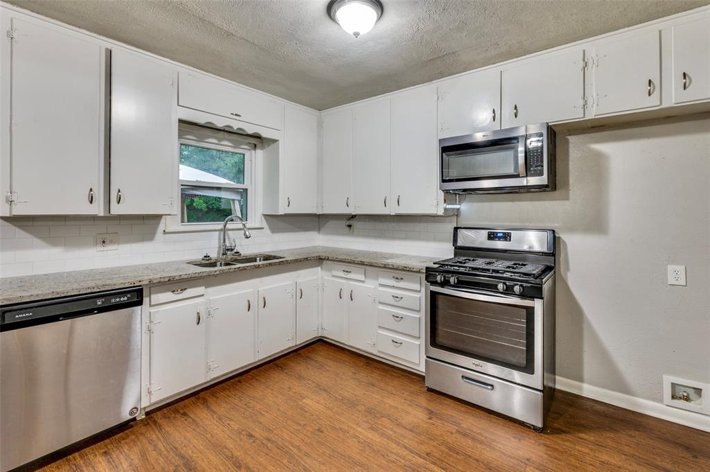 a kitchen with granite countertop white cabinets and stainless steel appliances