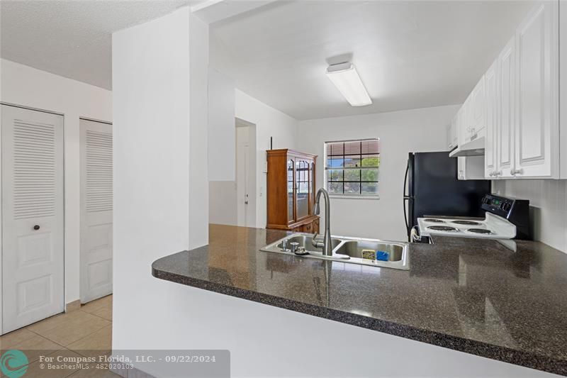 a view of a kitchen with kitchen island a sink appliances and cabinets