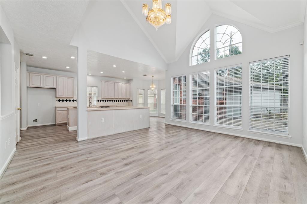 a view of an empty room with kitchen and wooden floor