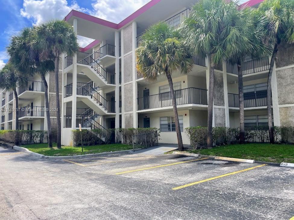 a front view of multi story residential apartment building with yard and sign board