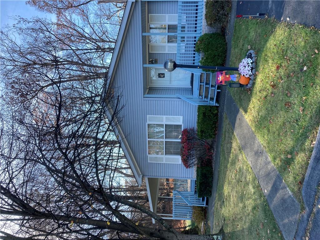 a view of a house with a yard chairs and a large tree