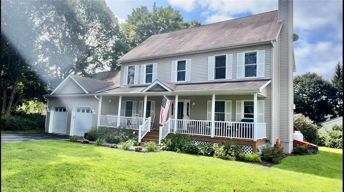 View of front of house with a porch, a front yard, and a garage