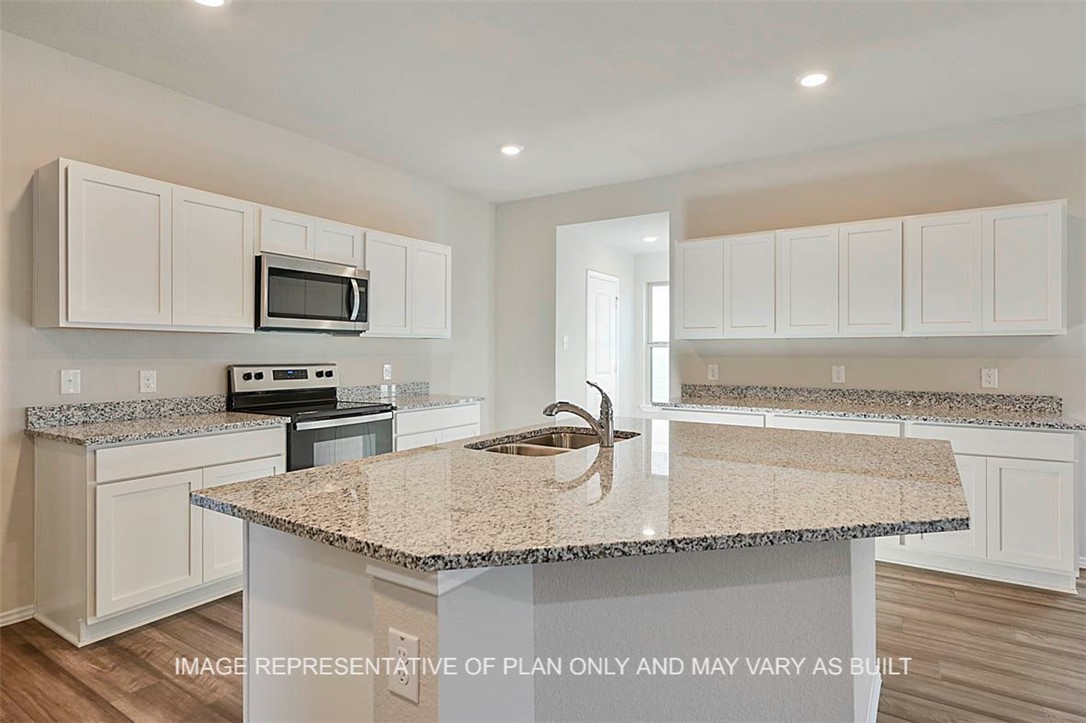 a kitchen with granite countertop a sink stainless steel appliances and white cabinets