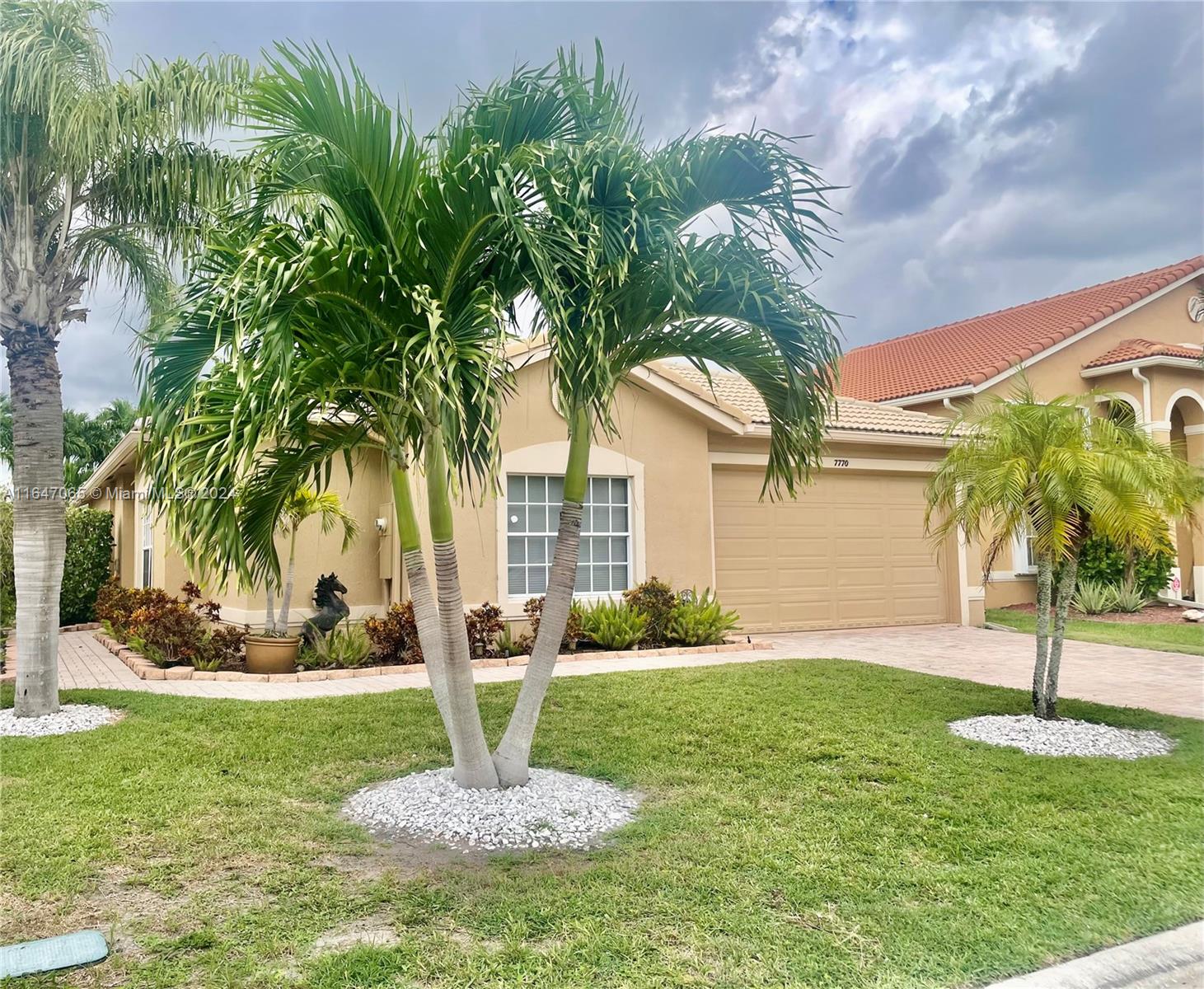 a front view of a house with a yard and palm trees