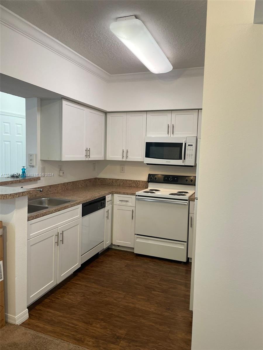 a kitchen with granite countertop white cabinets and stainless steel appliances