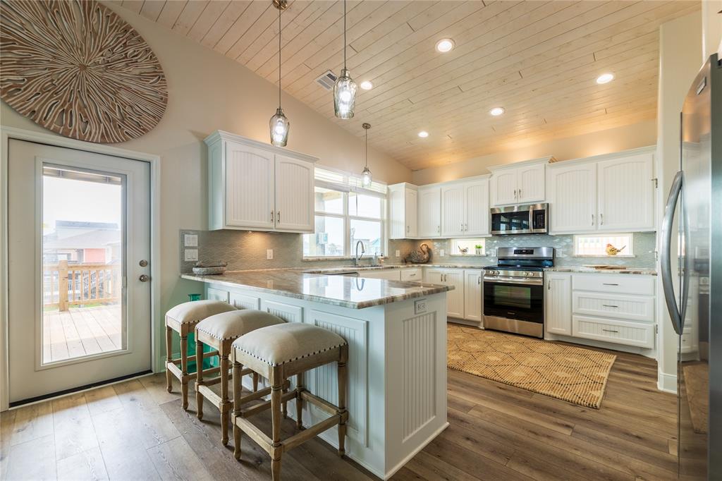 a kitchen with granite countertop kitchen island stainless steel appliances a stove a sink a refrigerator and cabinets