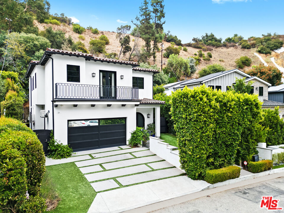 a front view of a house with a yard and potted plants