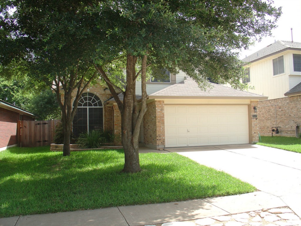 a front view of a house with a yard and tree