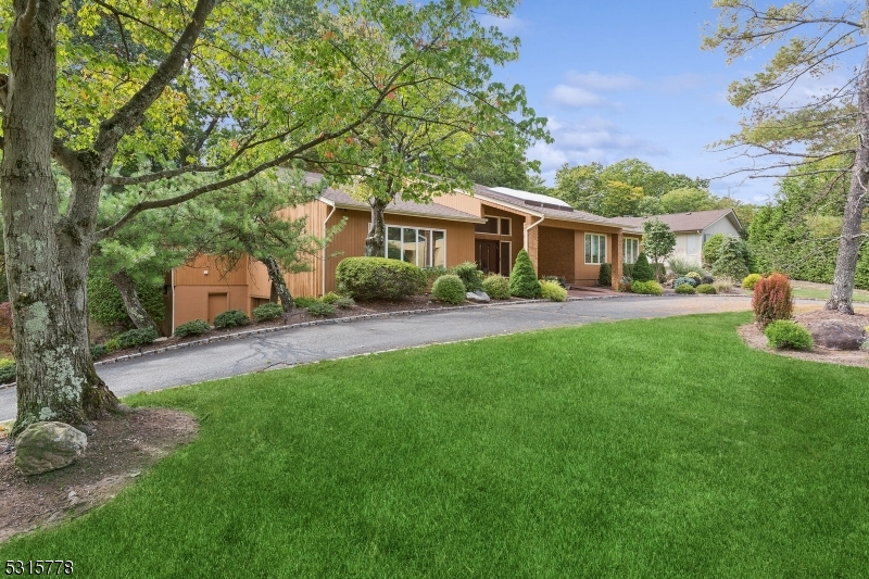 a front view of a house with a garden and trees