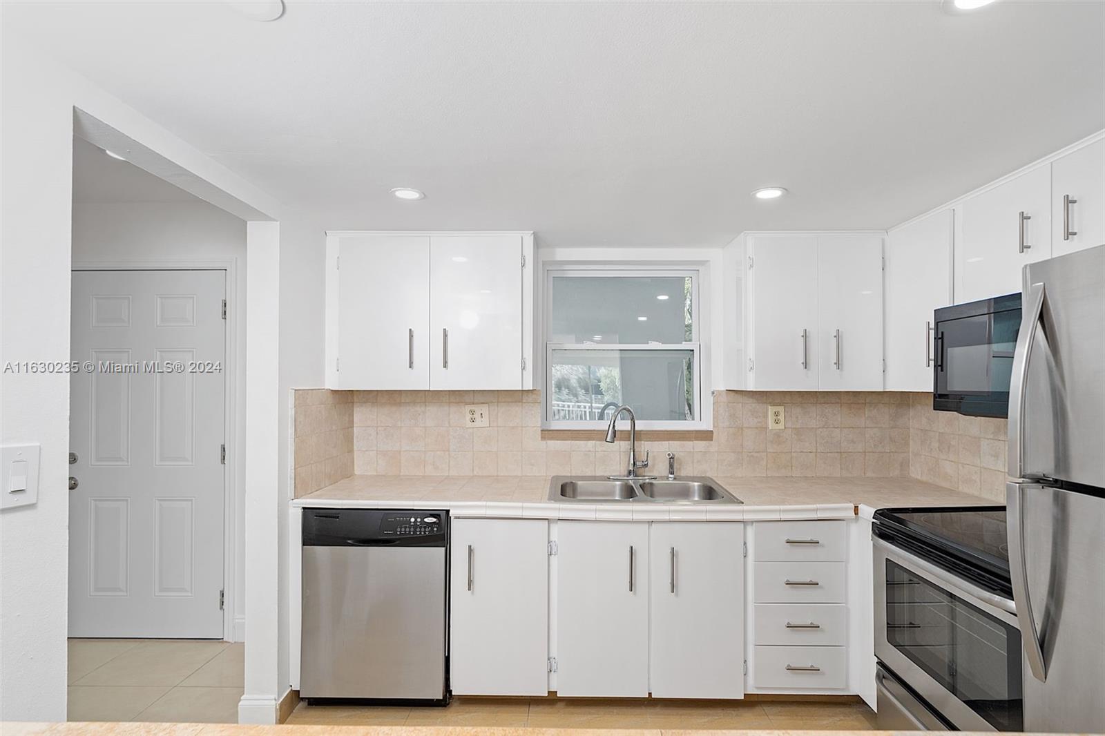 a kitchen with granite countertop white cabinets and stainless steel appliances