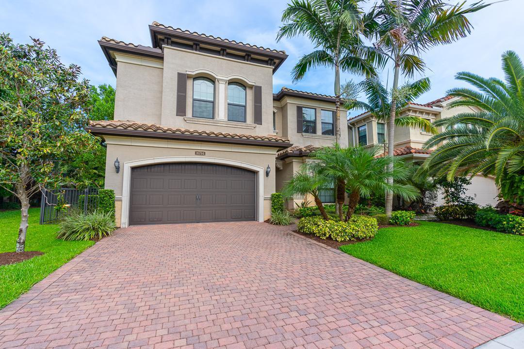 a front view of a house with a garden and palm trees