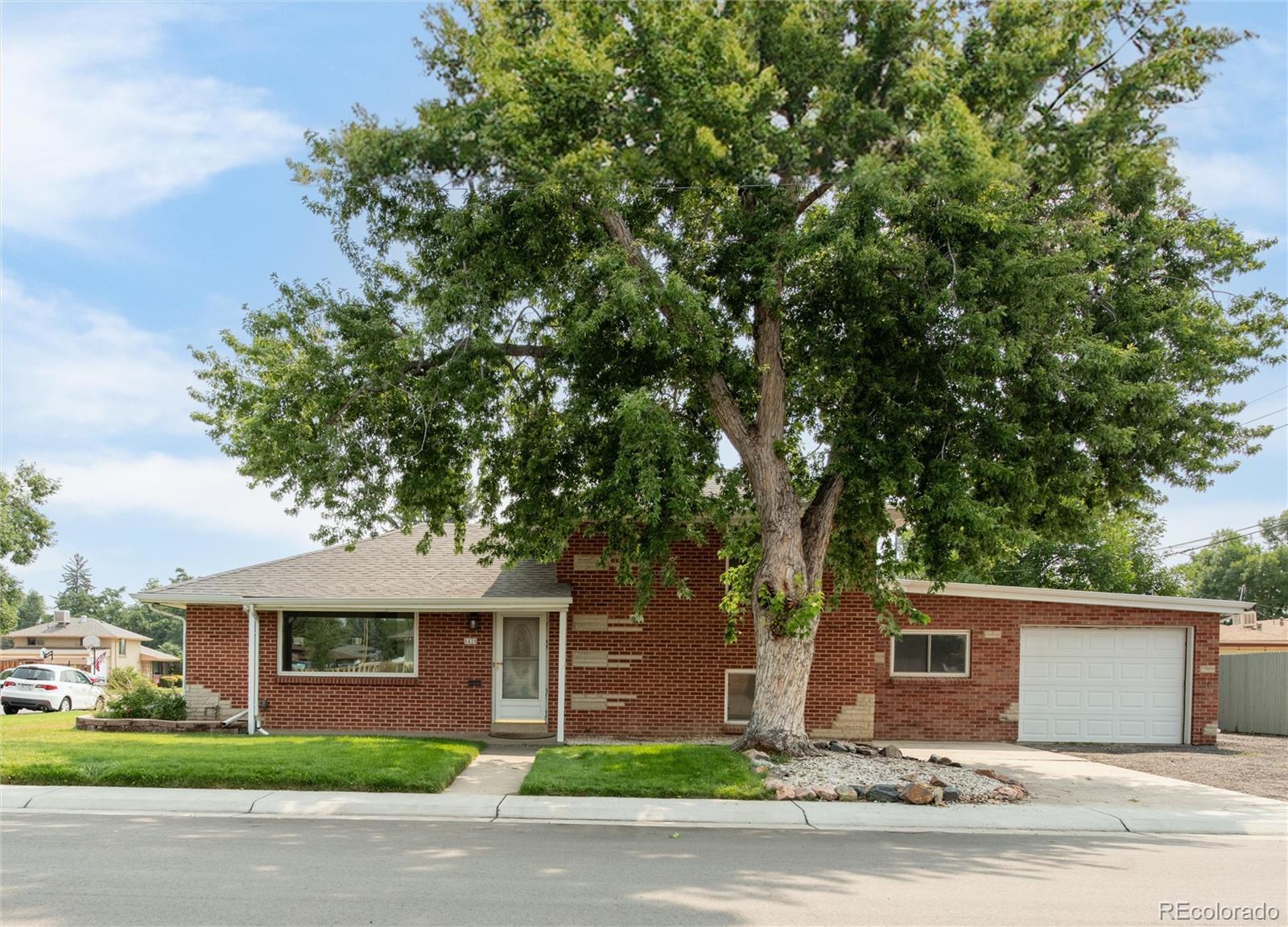 a front view of a house with a garden and tree