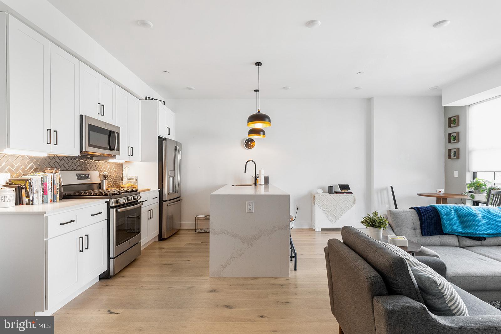 a living room with stainless steel appliances furniture and a kitchen view