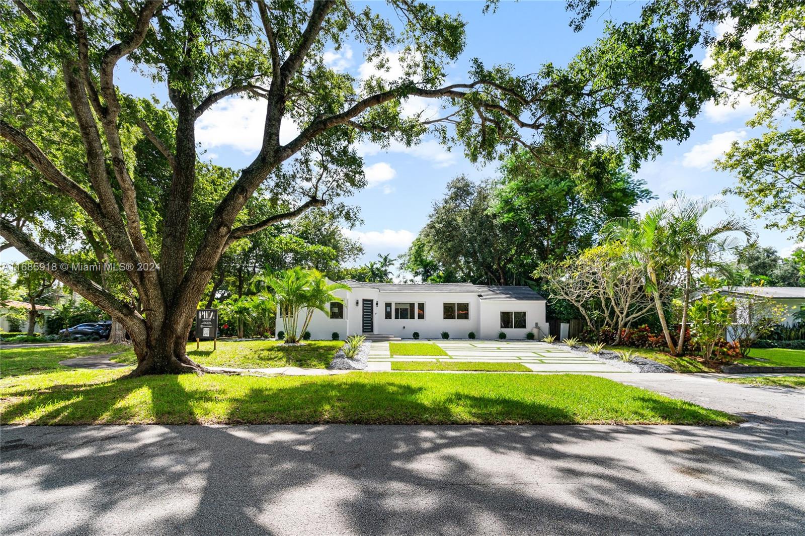 a view of a house with a big yard and large trees