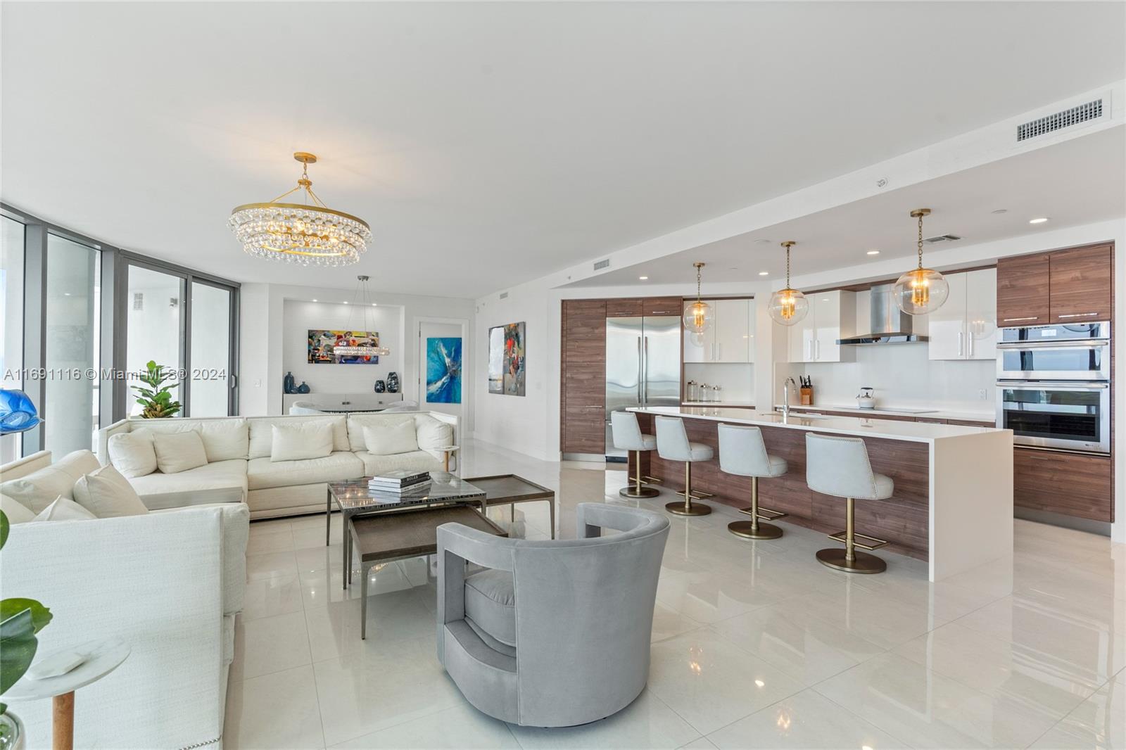 a living room with couches and kitchen view with wooden floor