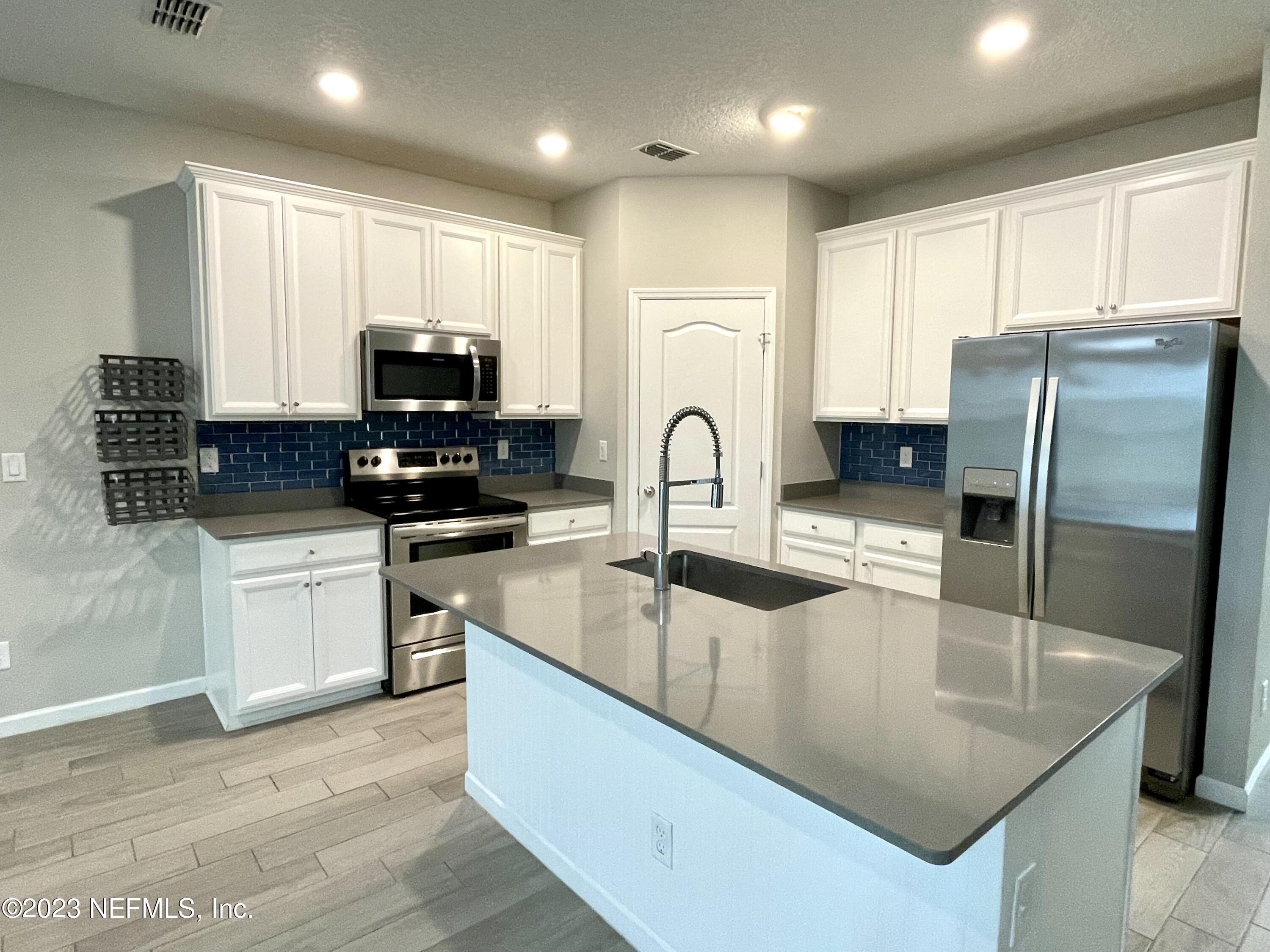 a kitchen with stainless steel appliances granite countertop a sink a stove a refrigerator cabinets and a kitchen island