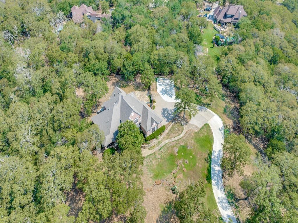 an aerial view of residential house with outdoor space and trees all around