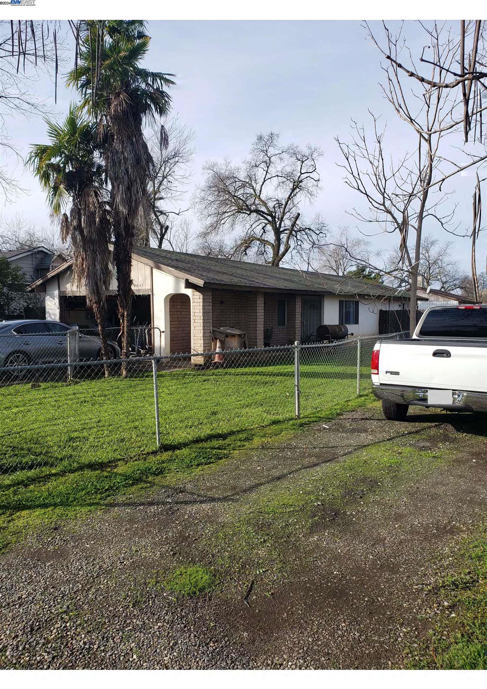 a view of a house with a yard and palm trees