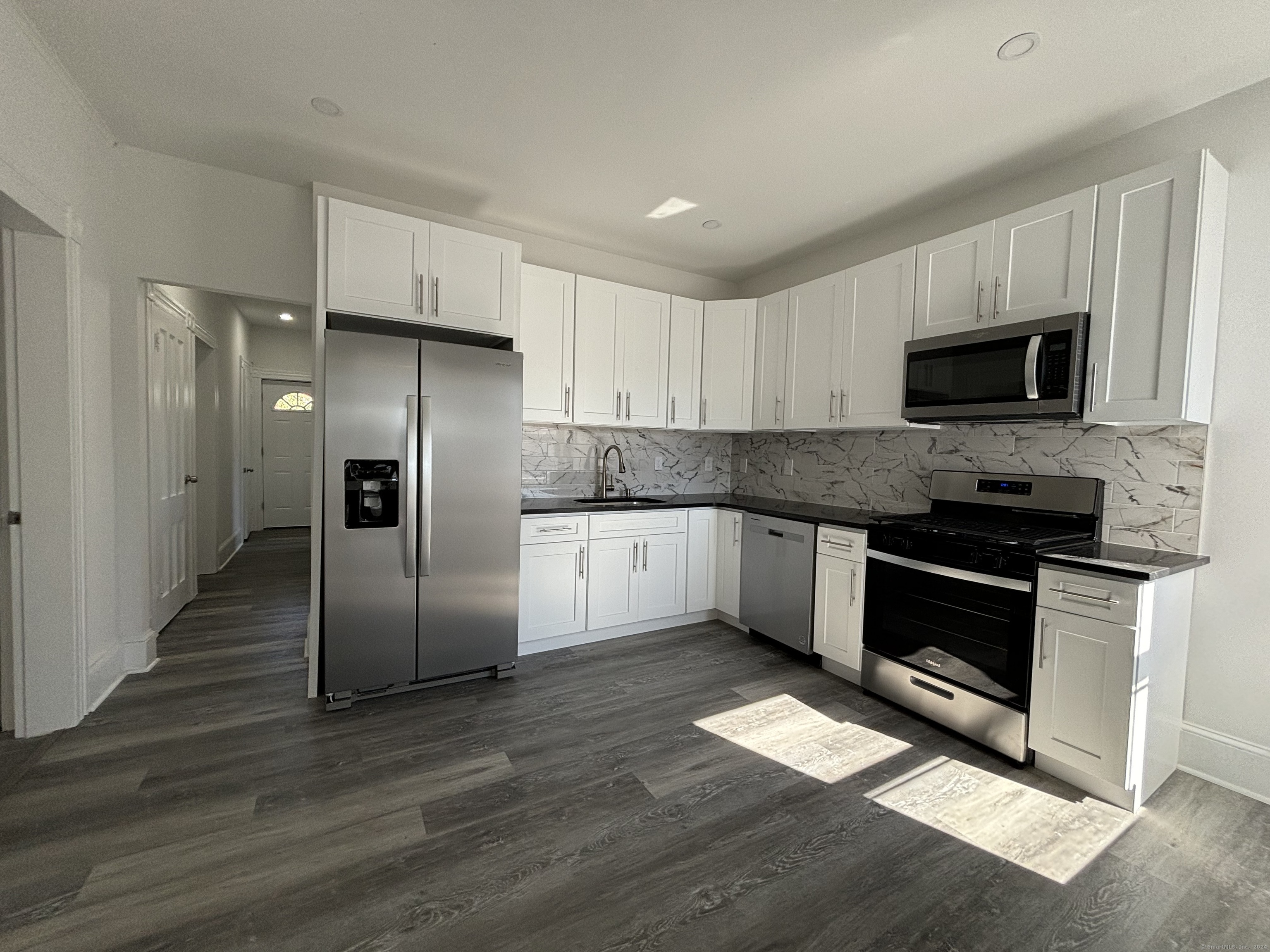 a kitchen with granite countertop a refrigerator stove and microwave