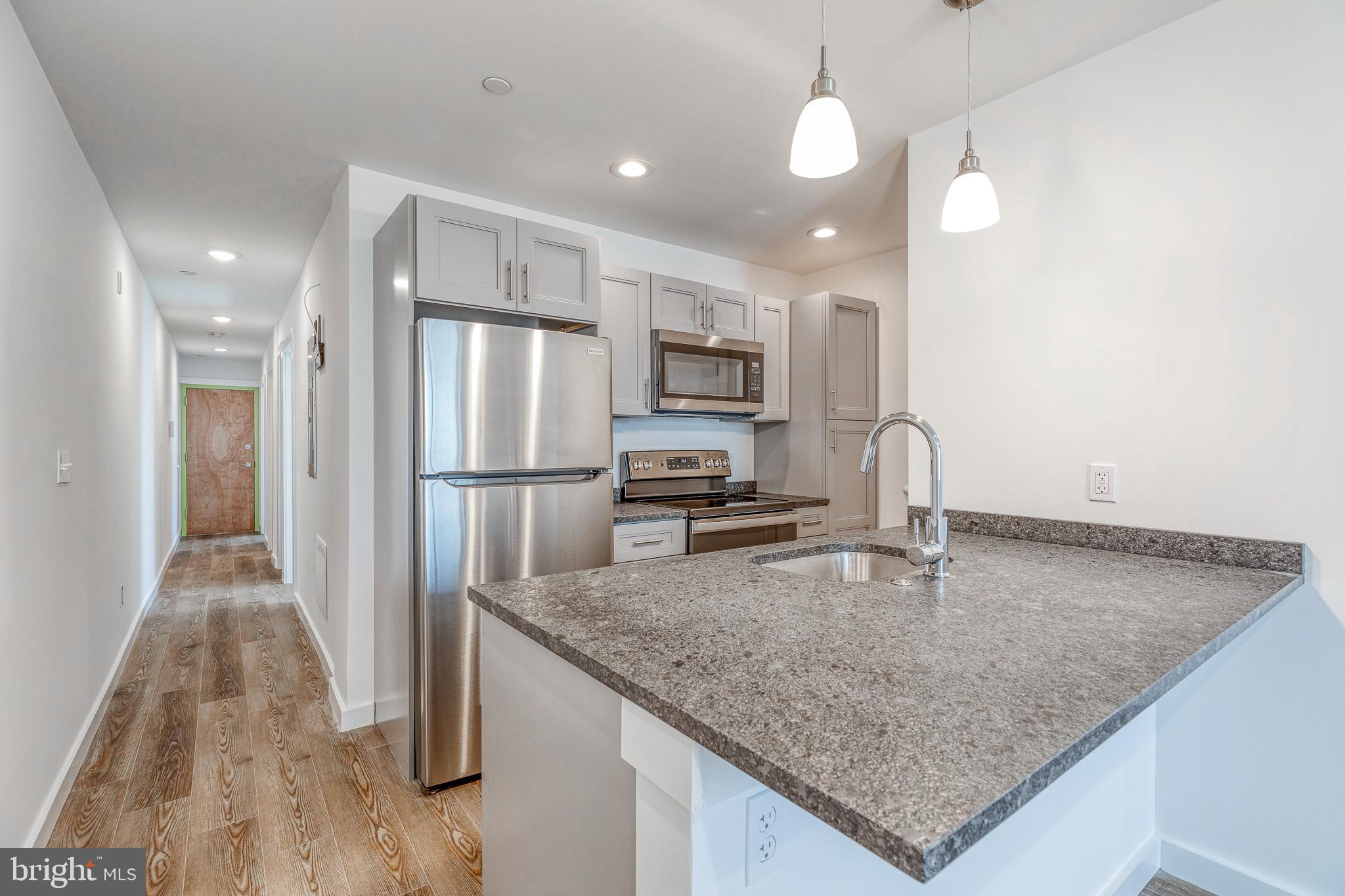 a kitchen with stainless steel appliances granite countertop a sink refrigerator and microwave