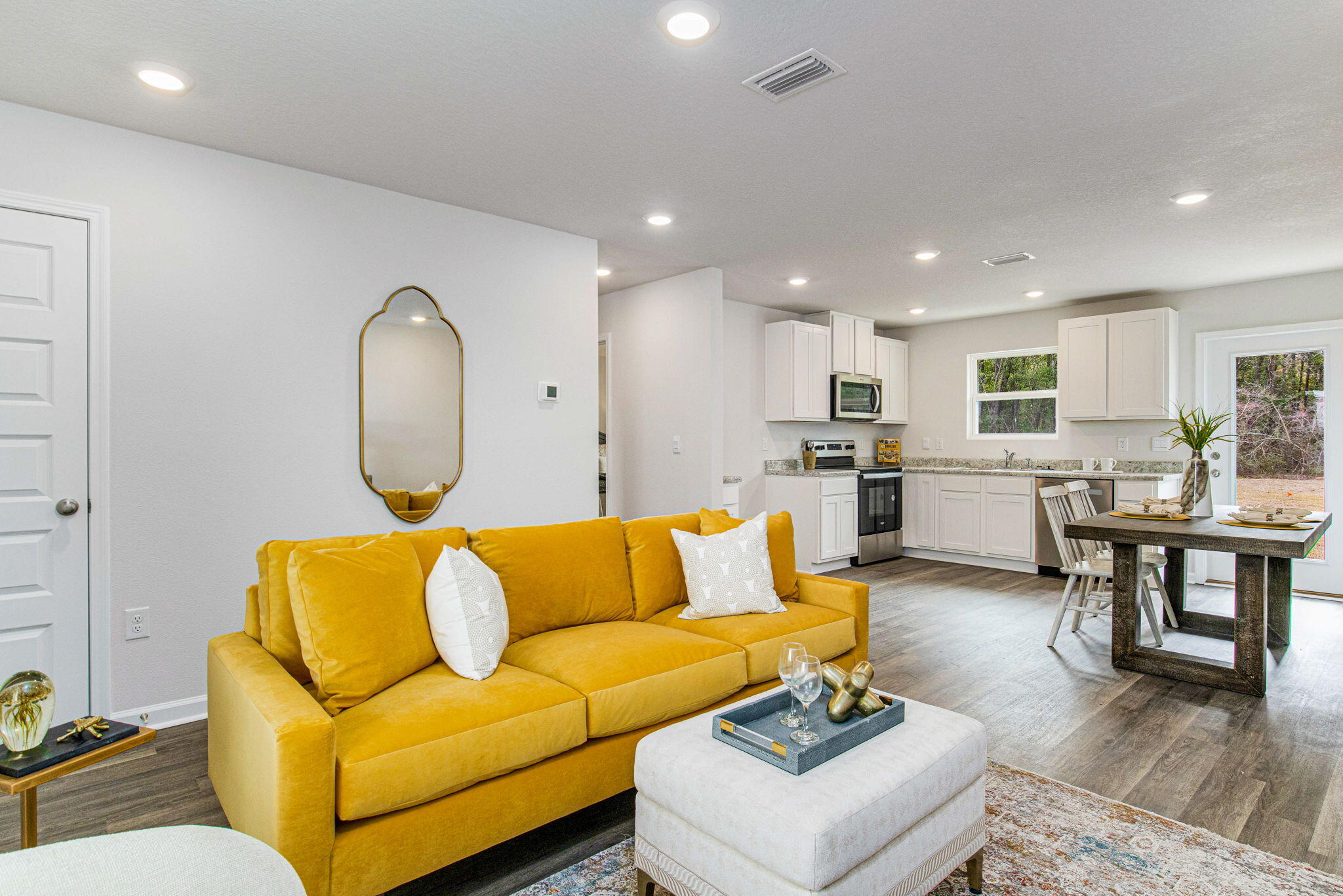 a living room with furniture kitchen view and a wooden floor