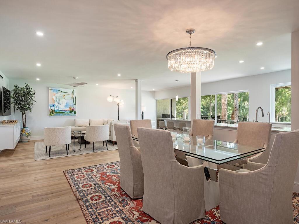 a dining room with wooden floor a chandelier a wooden table and chairs