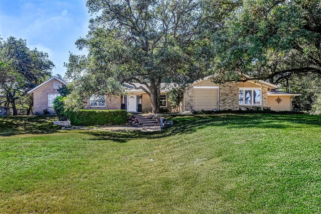 a view of a house with a big yard and large trees