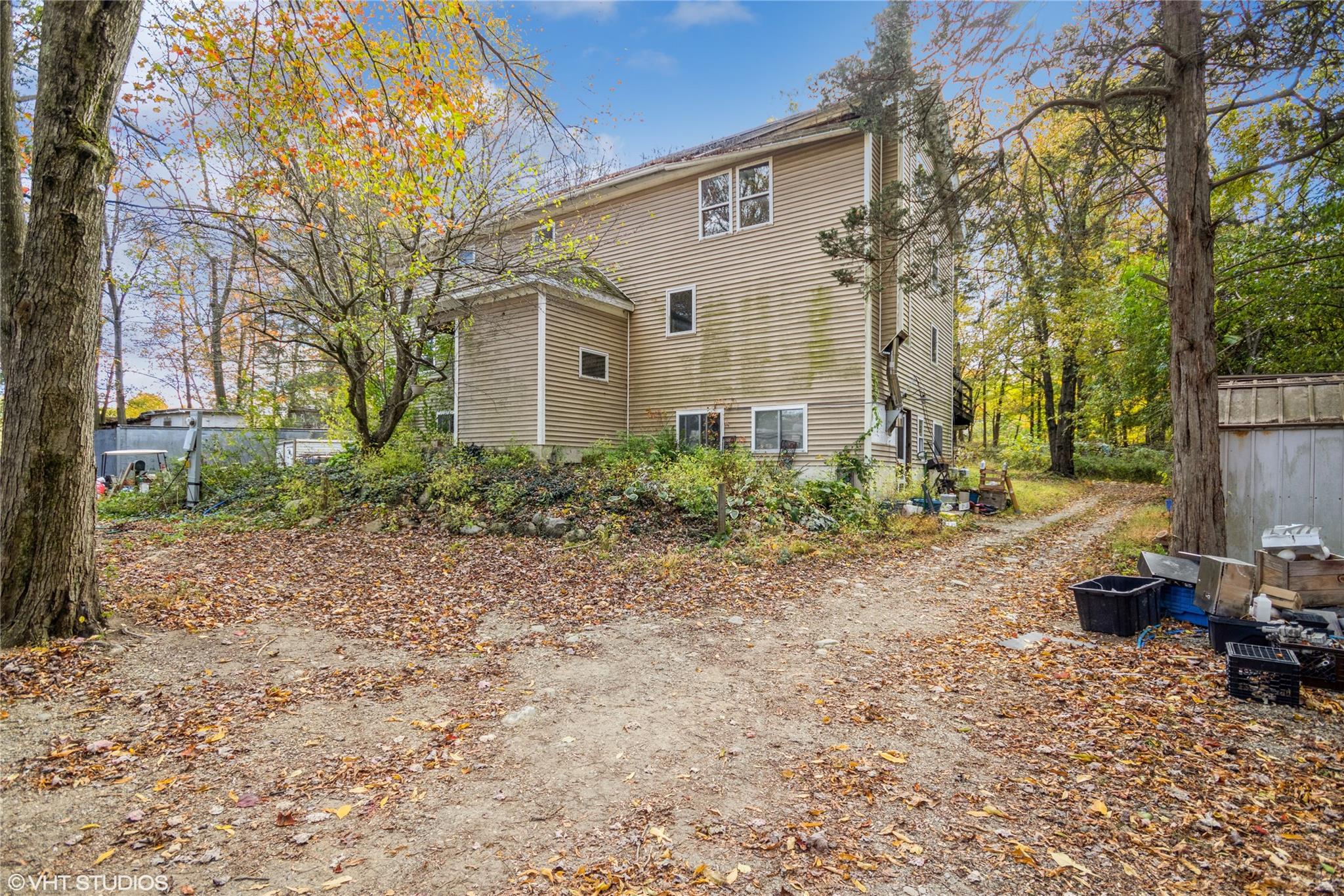 a backyard of a house with plants and large tree