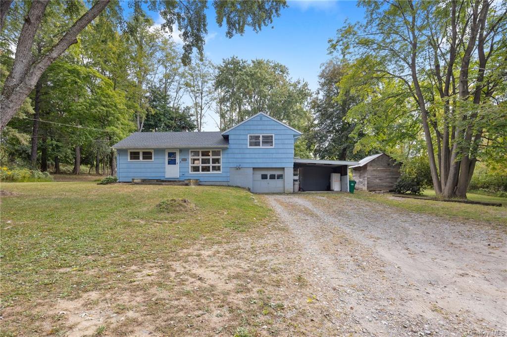 Tri-level home featuring a front lawn and a carport