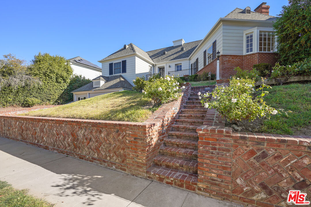 a view of a house with a yard and potted plants