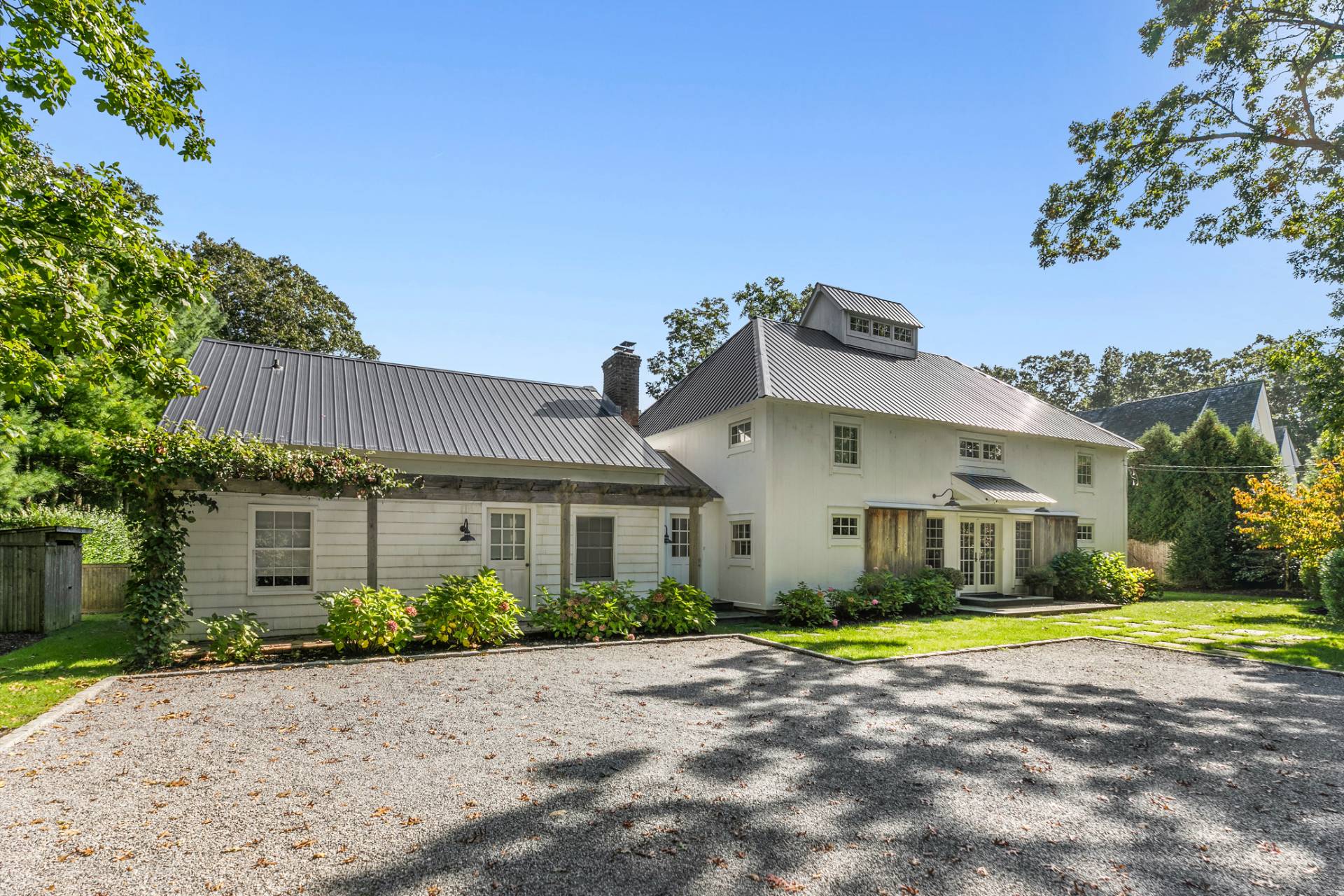 a view of a white house with a big yard and large trees