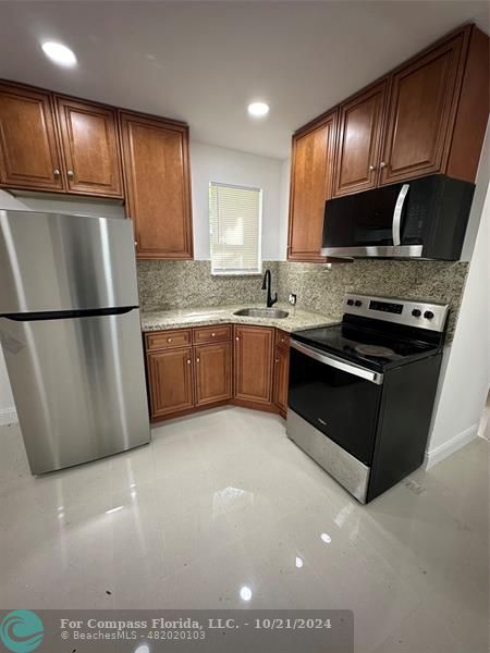 a kitchen with granite countertop a sink a stove and refrigerator