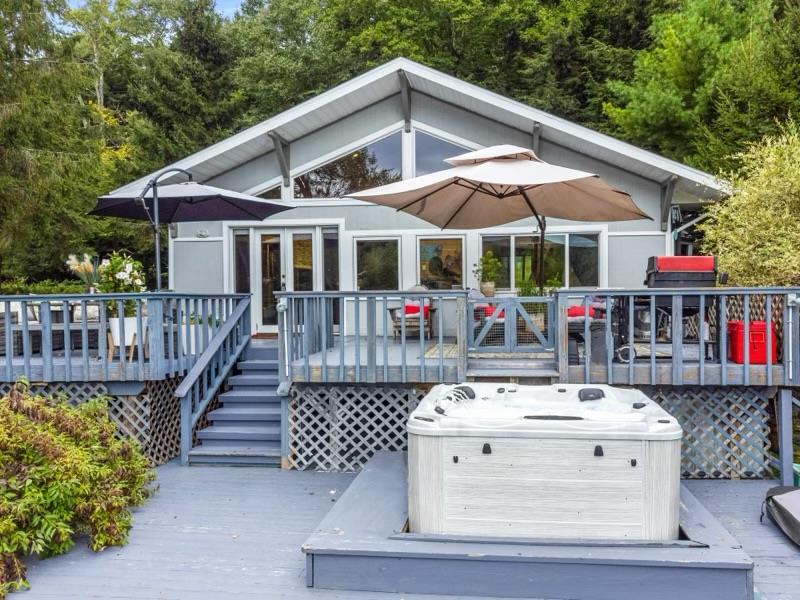 Rear view of house featuring a wooden deck and a hot tub