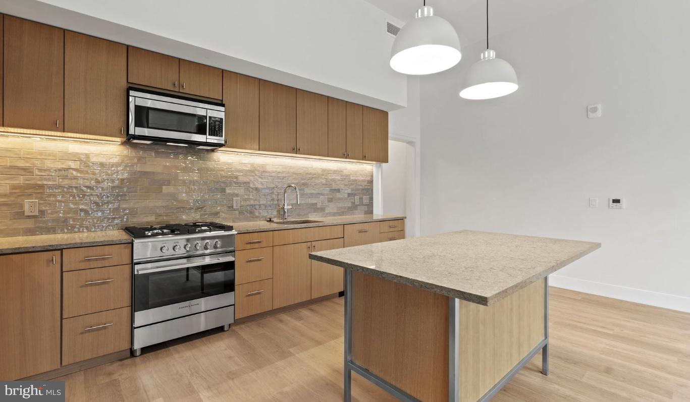 a kitchen with granite countertop cabinets stainless steel appliances and wooden floor