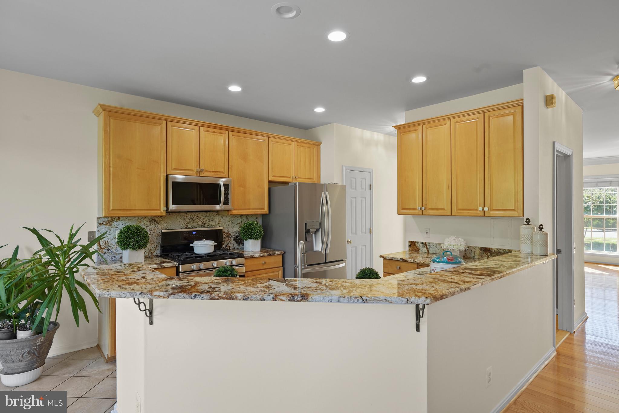 a kitchen with stainless steel appliances granite countertop sink a refrigerator a microwave a stove and white cabinets