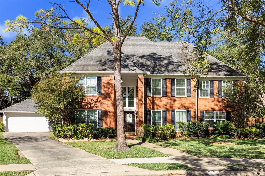 This is a two-story brick home featuring a detached garage, a well-manicured lawn, and mature trees, situated in a pleasant neighborhood.