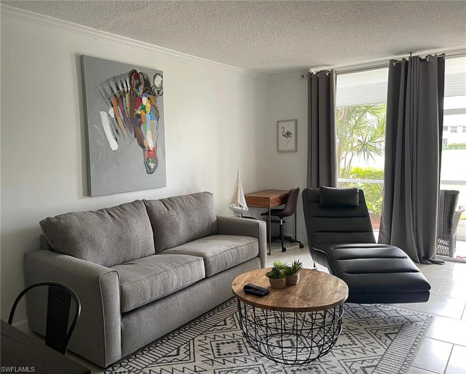 Living room featuring tile patterned floors, crown molding, and a textured ceiling