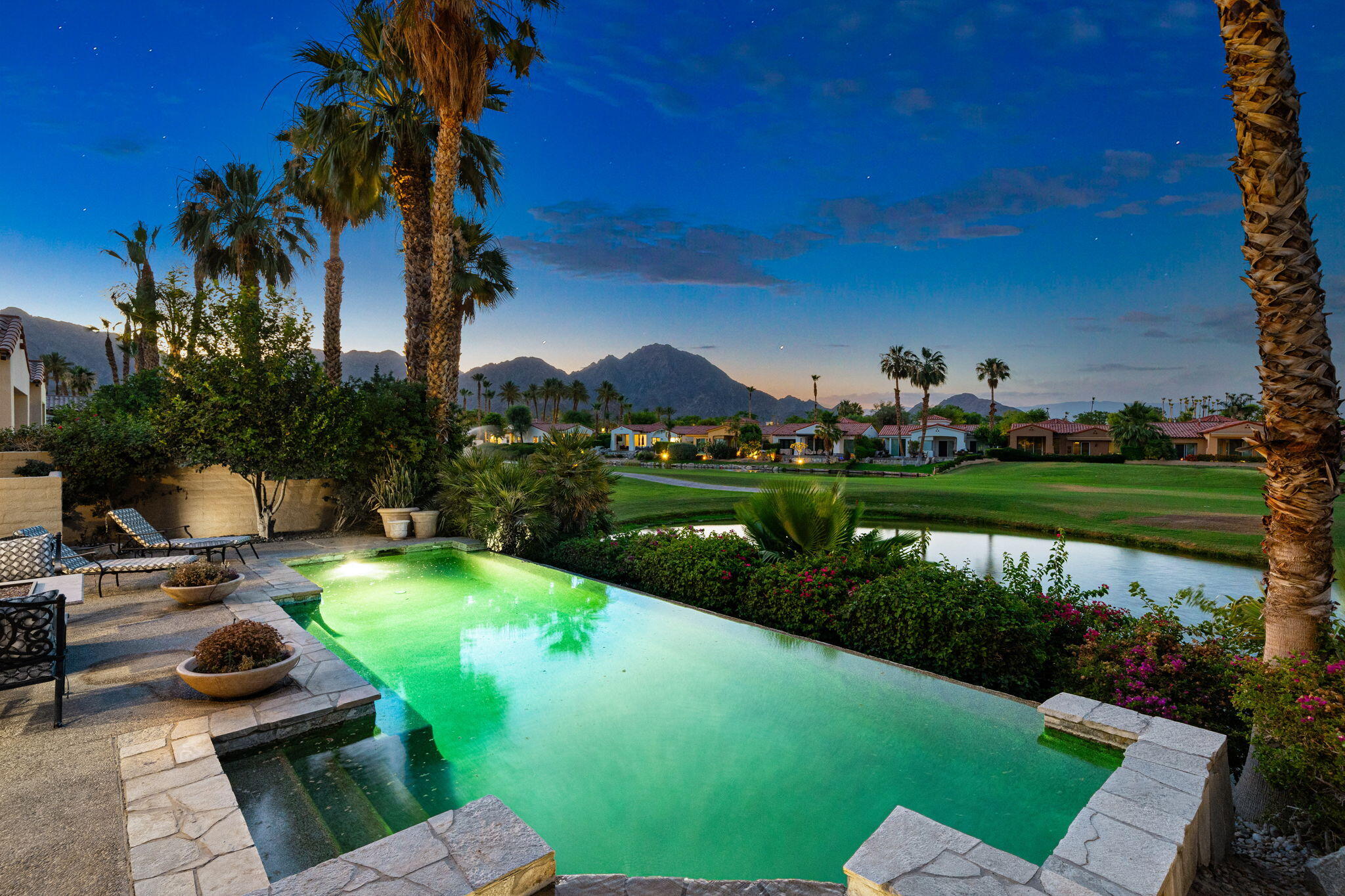 a view of a swimming pool and lounge chairs in back of the house