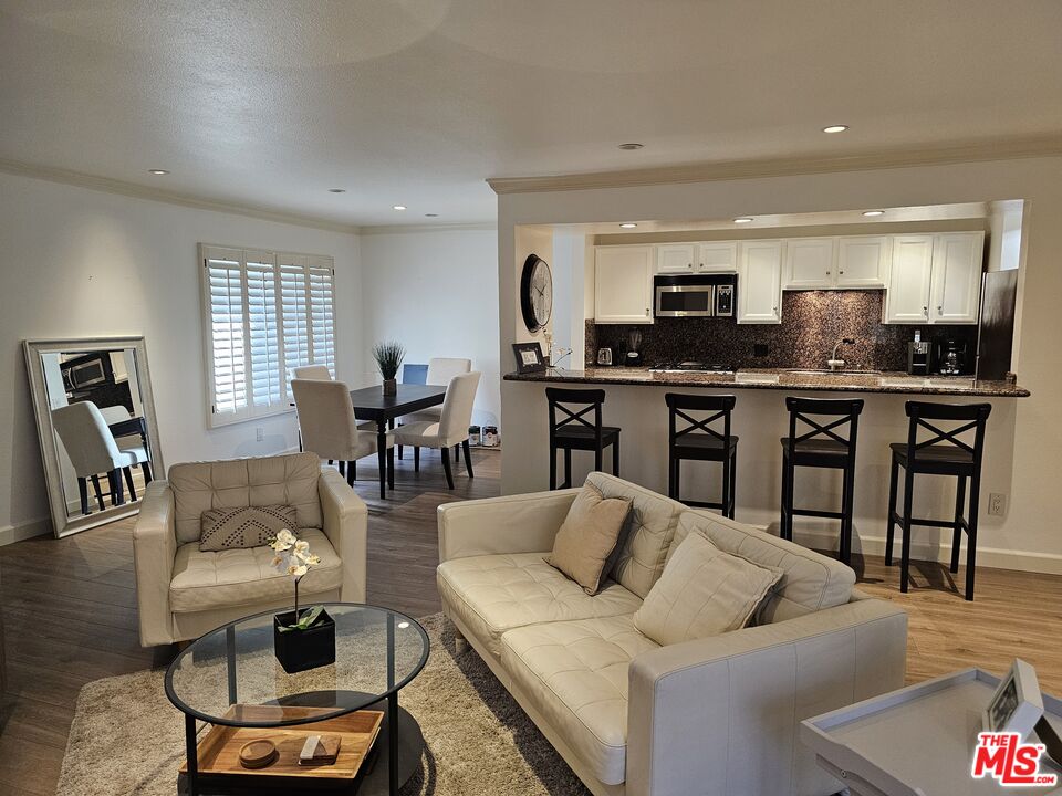 a living room with furniture kitchen view and a wooden floor