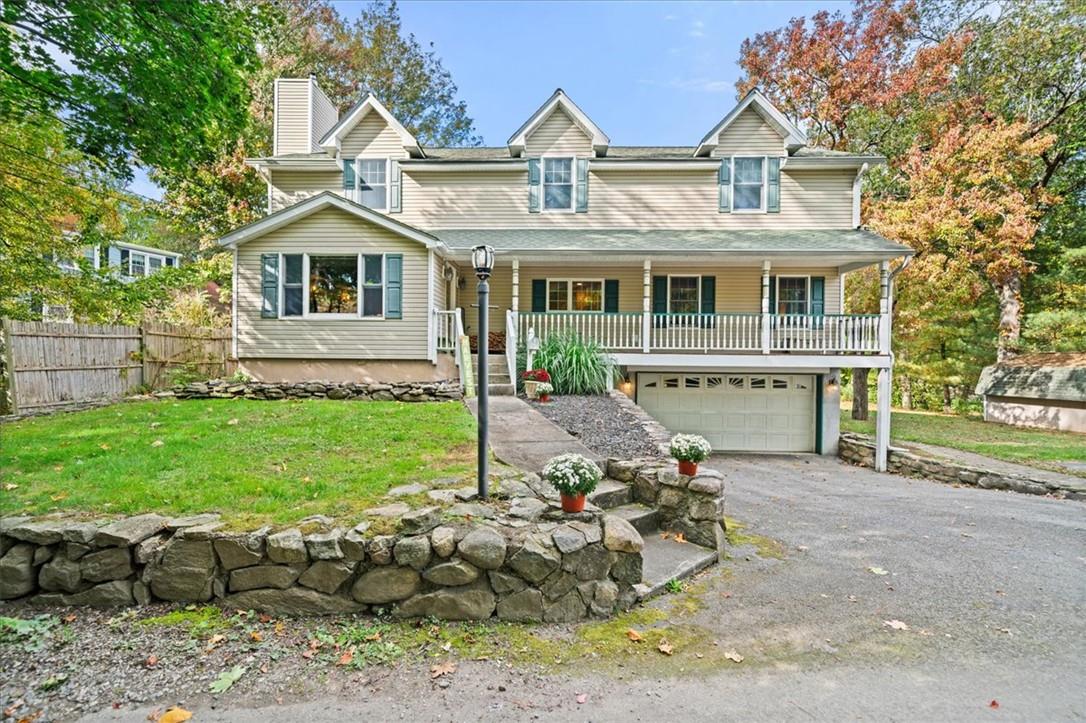 View of front of home featuring covered porch, a front yard, and a garage