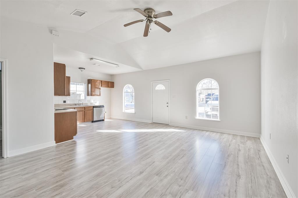 a view of kitchen and empty room with wooden floor