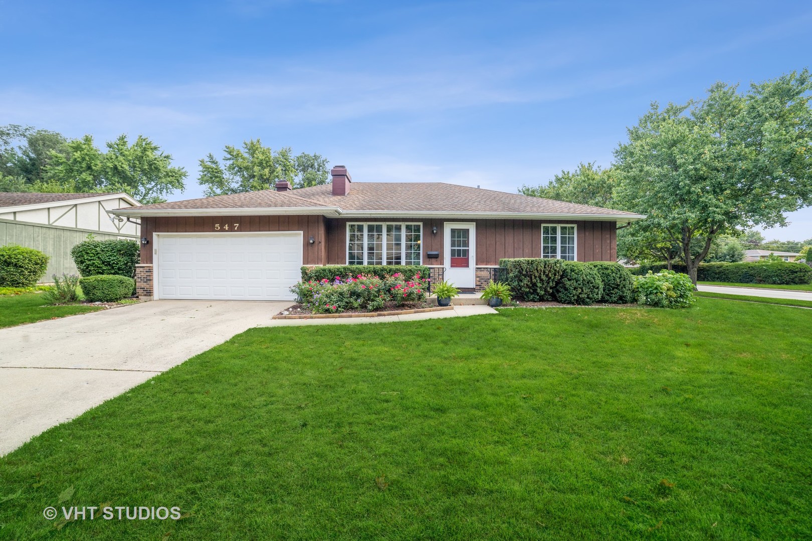 a front view of a house with a yard and green space