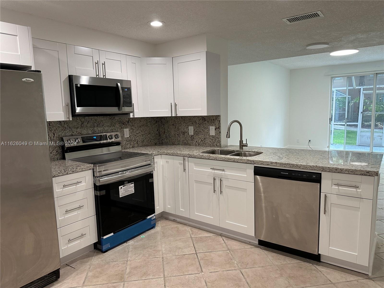 a kitchen with granite countertop a sink stove and microwave